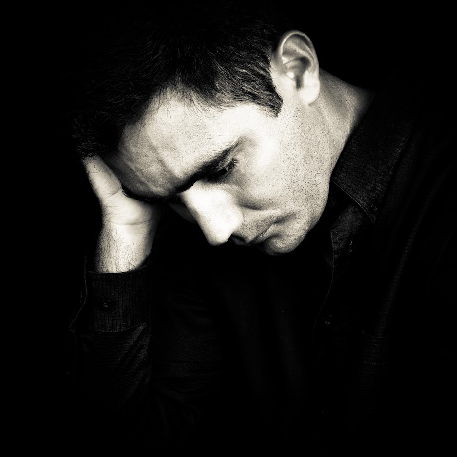 Black and white portrait of a worried and depressed man isolated on black