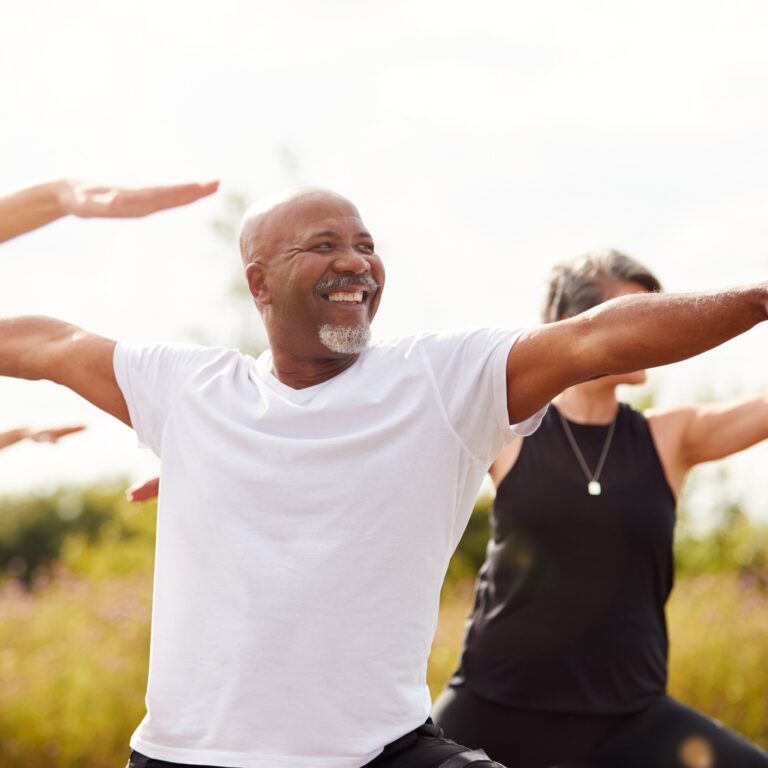 Group Of Mature Men And Women In Class At Outdoor Yoga Retreat