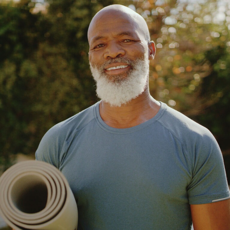 Cropped portrait of a happy senior man standing alone before a yoga session in his back garden