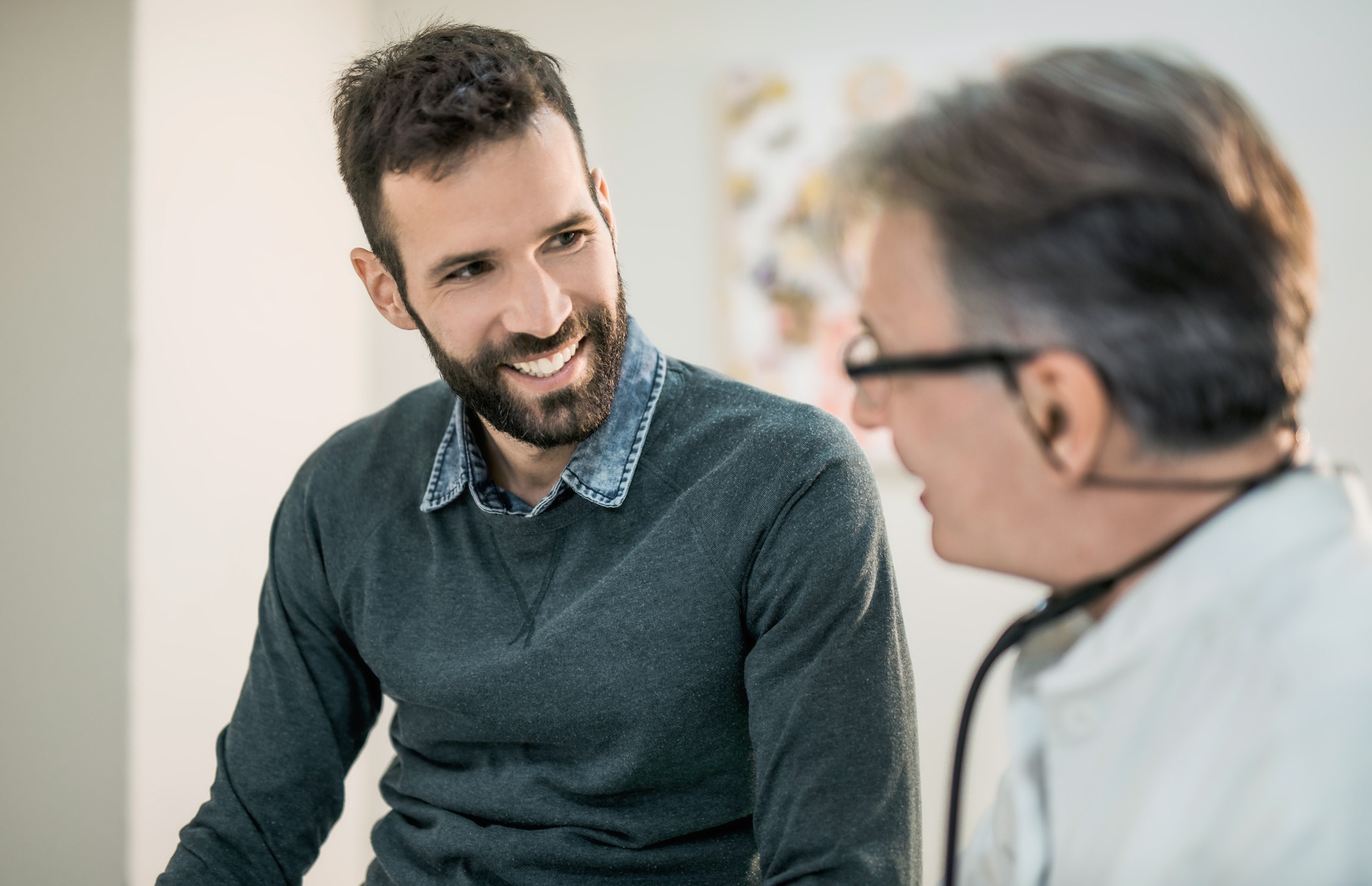 Happy mid adult male patient talking with his doctor.